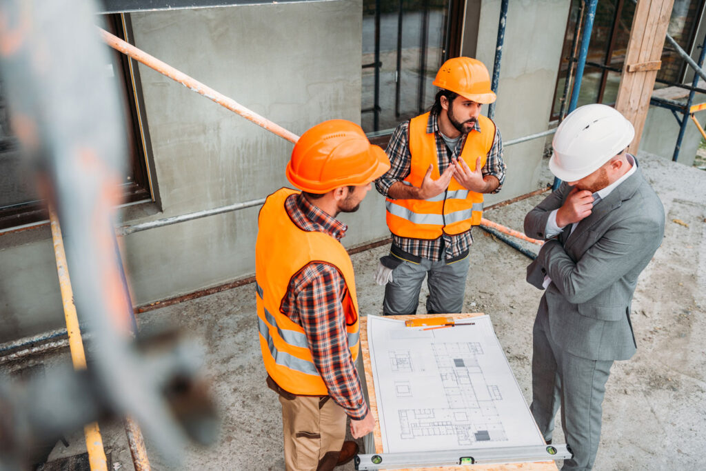 men going over mini excavator parts like the control lever before repairing sewer lines